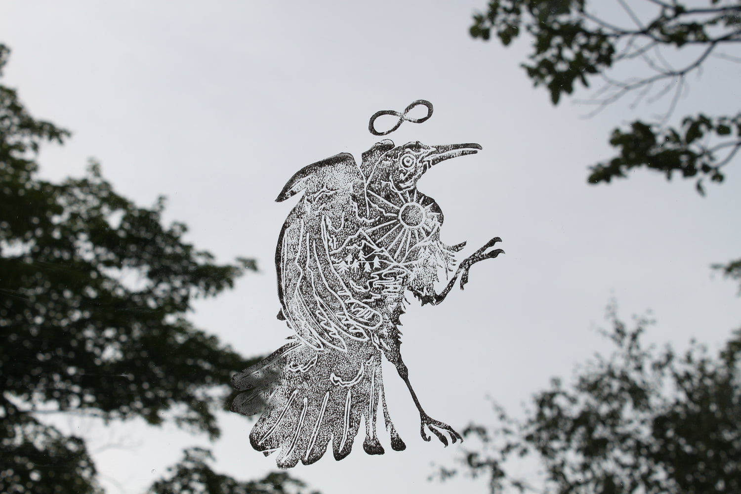 Printed bird on glass, facing to the right, with trees in the background.