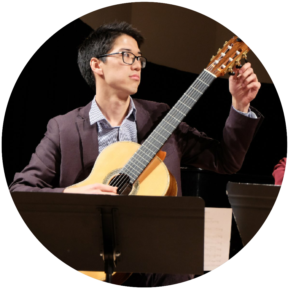 Circular image of person with short dark hair and glasses, tuning a guitar.