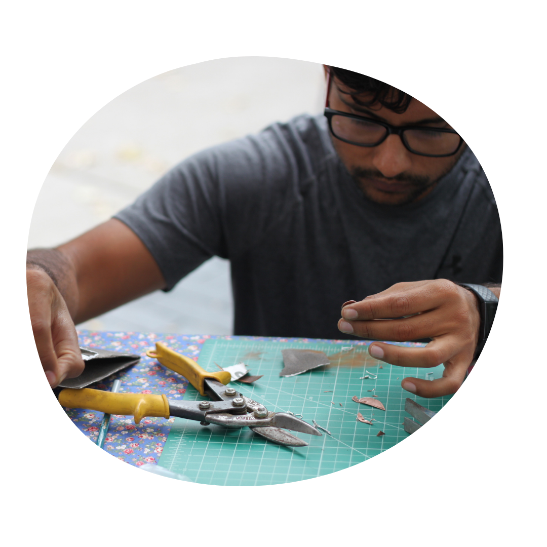 Person holds copper material with pliers in front of them at a table.