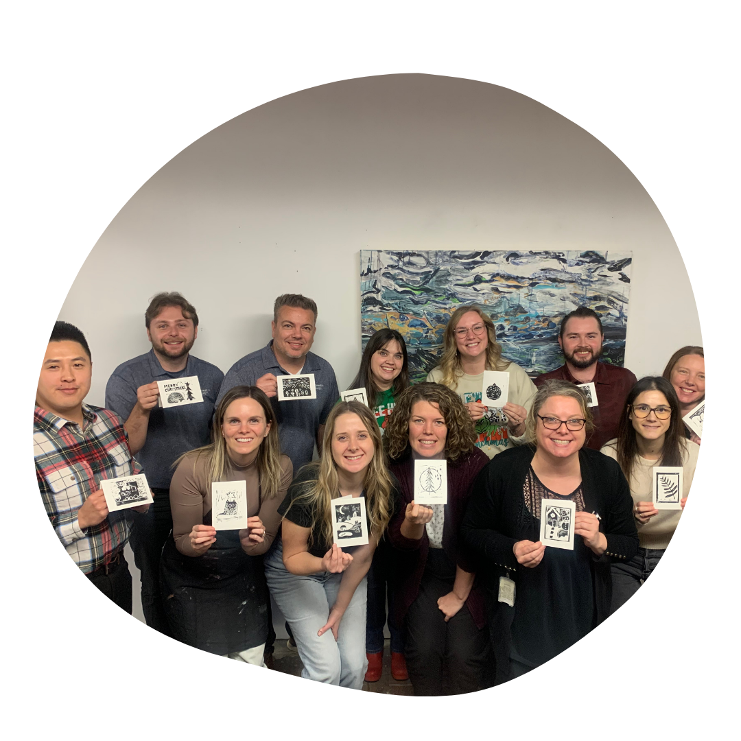 Group of people smile while holding up linoblock prints.