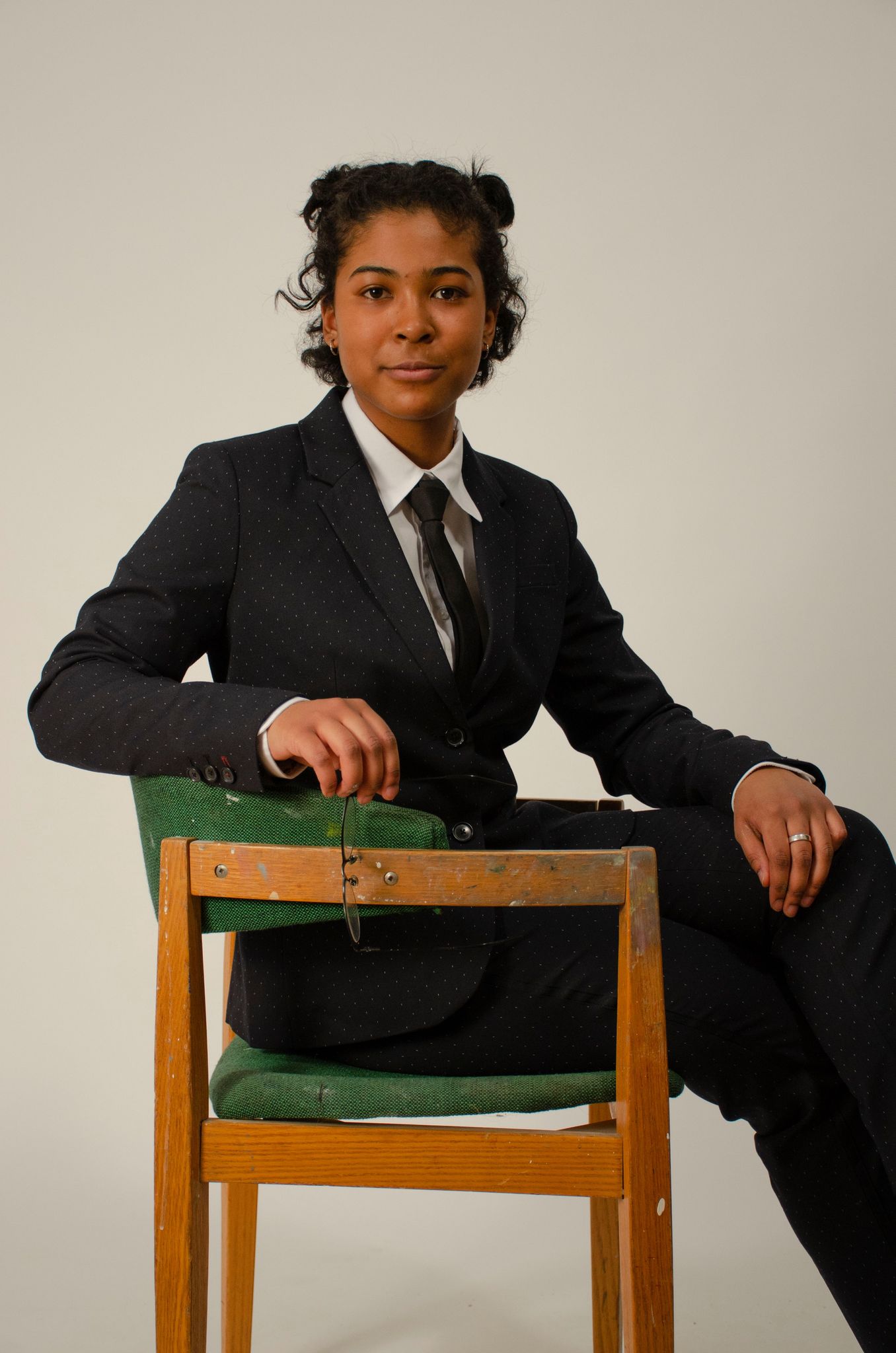 Person sits in a chair with a suit on.